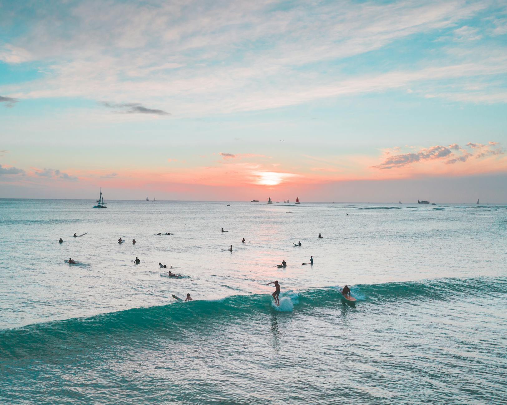 Surferzy na tropikalnej plaży Indonezji o zachodzie słońca