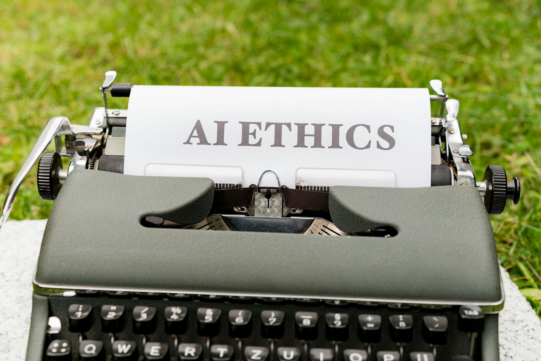Stara maszyna do pisania na zewnątrz z kartką z napisem AI ethics