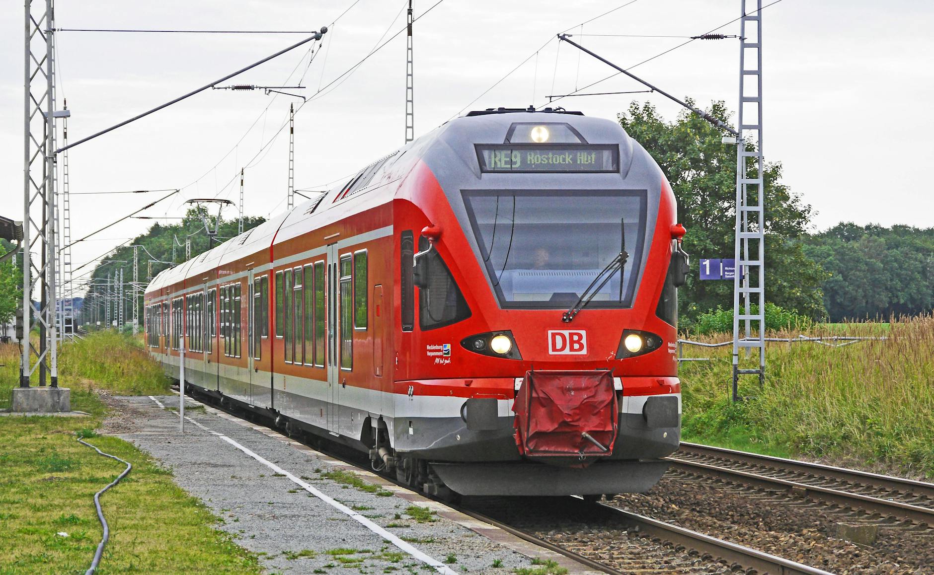 Czerwony pociąg elektryczny wjeżdża na małą wiejską stację w Niemczech