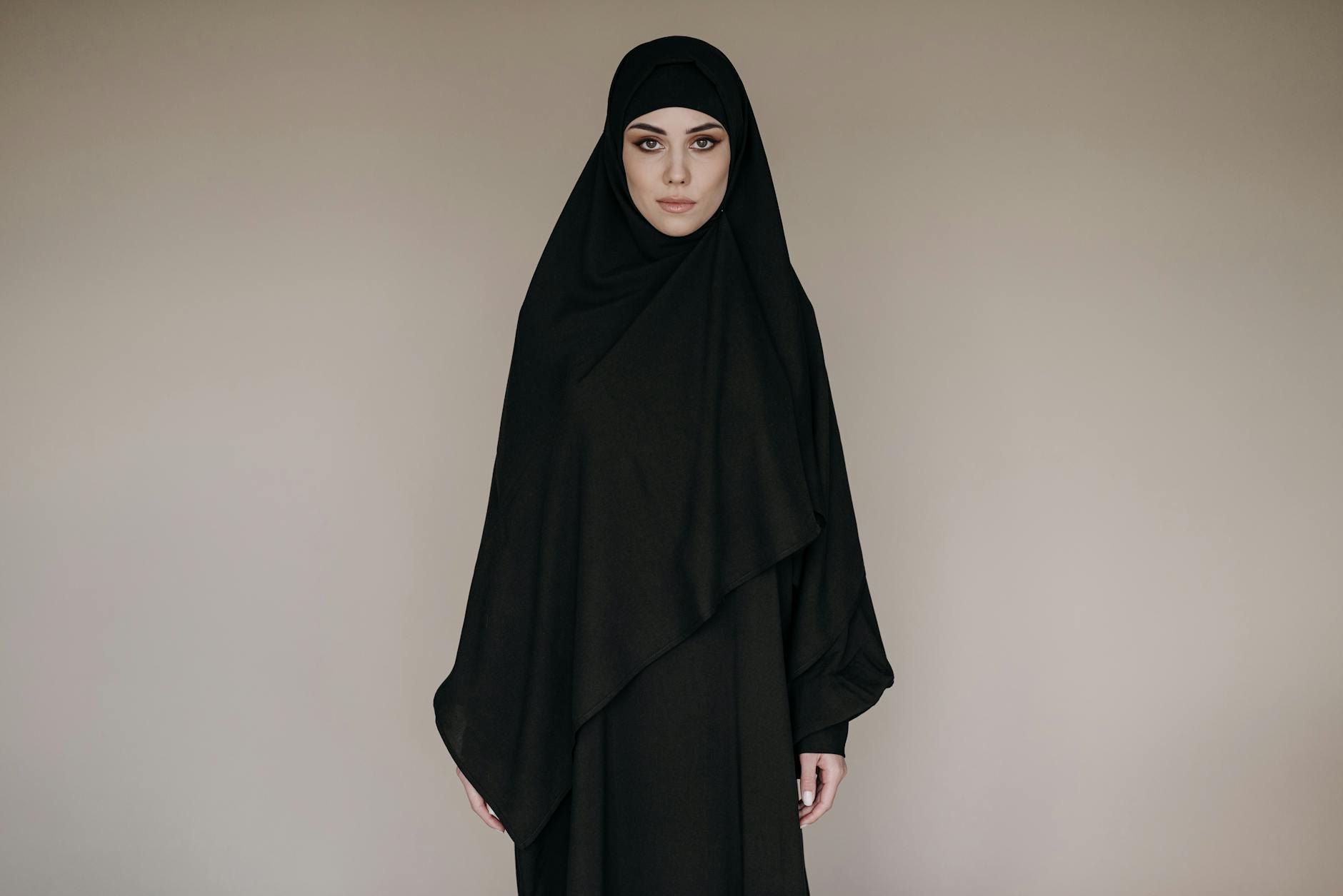 Saudyjska kobieta w eleganckim czarnym hidżabie na neutralnym tle