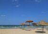 Kiedy jechać do Tunezji? Pogoda miesiąc po miesiącu i temperatura morza Słoneczna plaża w Tunezji ze słomianymi parasolami i błękitnym niebem